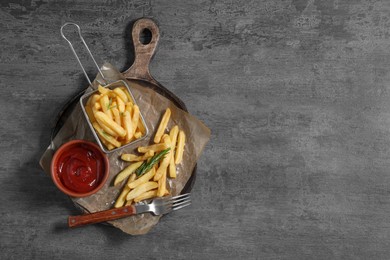 Photo of Tasty French fries, ketchup and rosemary on grey table, top view. Space for text