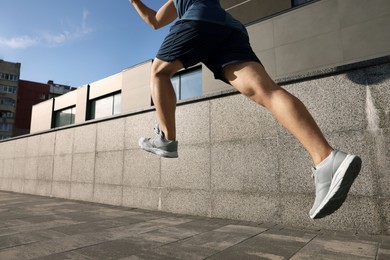 Photo of Man running near building outdoors, closeup. Space for text