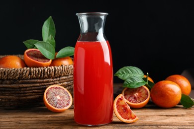 Photo of Tasty sicilian orange juice in glass bottle and fruits on wooden table