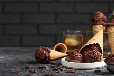 Photo of Tasty ice cream scoops, chocolate crumbs and waffle cones on dark textured table. Space for text
