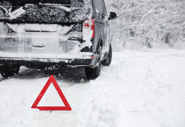 Emergency stop sign and modern car on snowy road