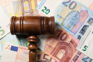 Tax law. Wooden gavel on euro banknotes, top view