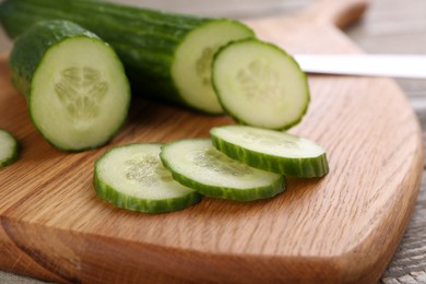 Photo of Fresh cucumbers on wooden cutting board, closeup