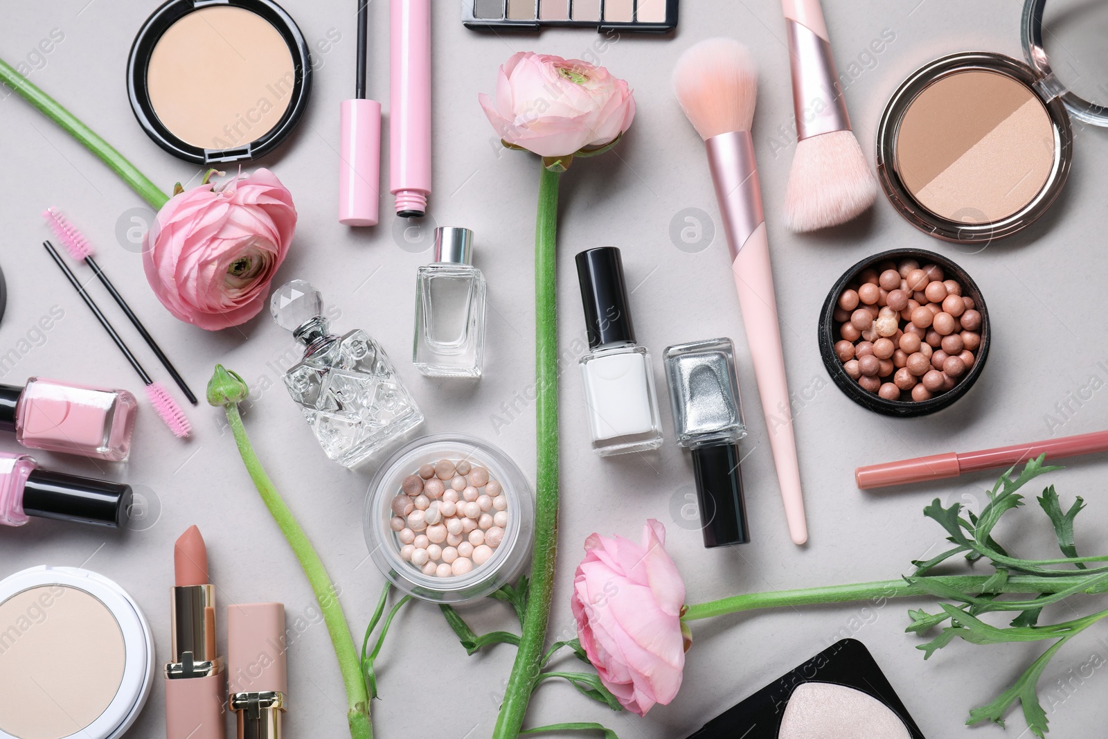 Photo of Flat lay composition with different makeup products and beautiful spring flowers on gray background