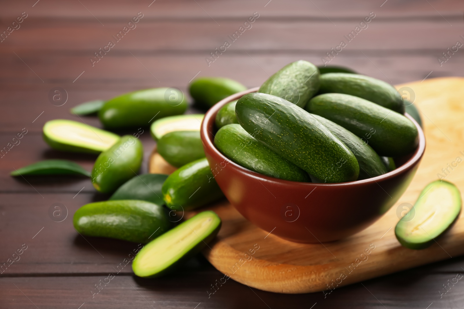 Photo of Fresh seedless avocados with green leaves on wooden table. Space for text