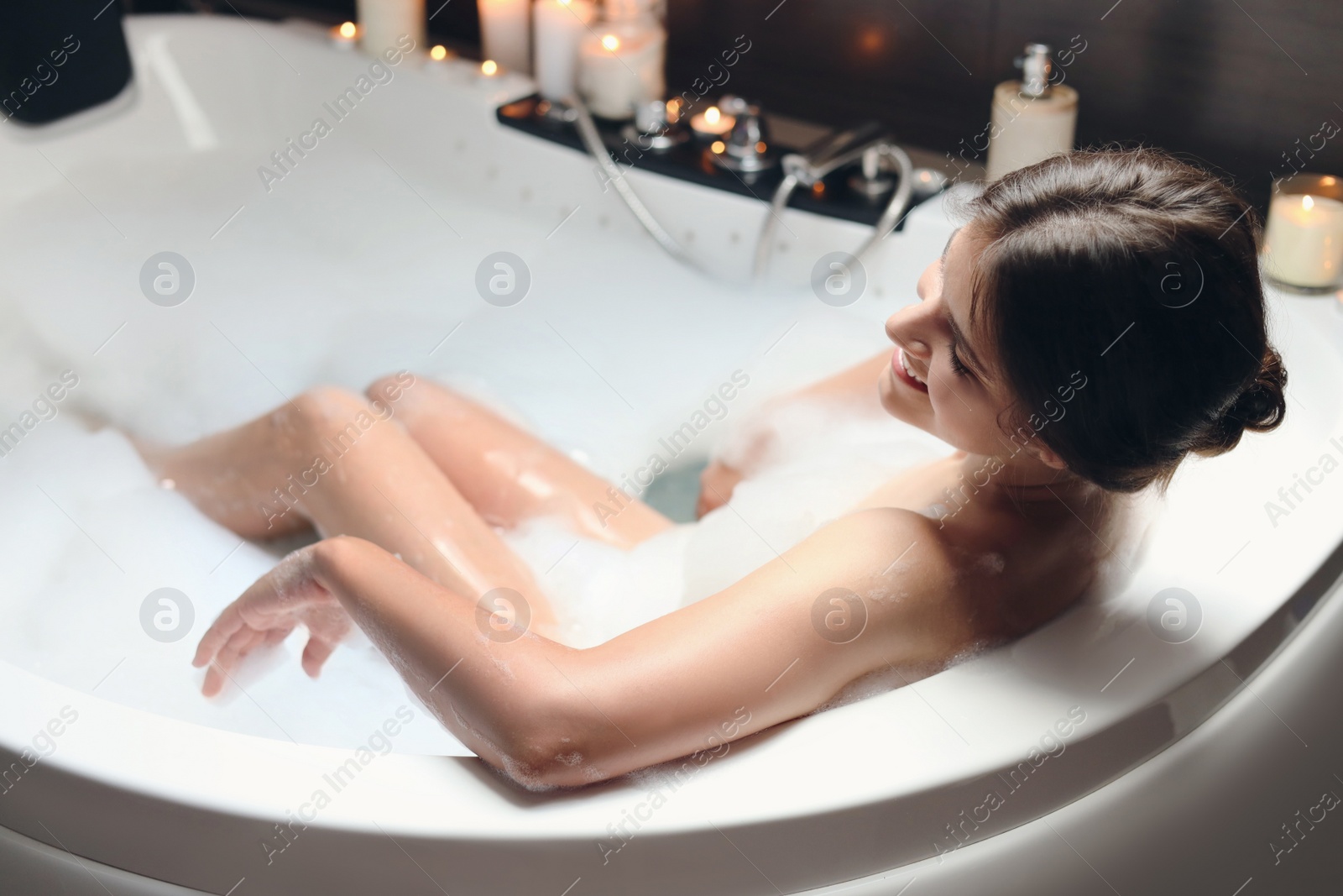 Photo of Happy beautiful woman taking bubble bath. Romantic atmosphere