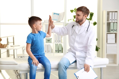 Children's doctor giving high five to patient in hospital
