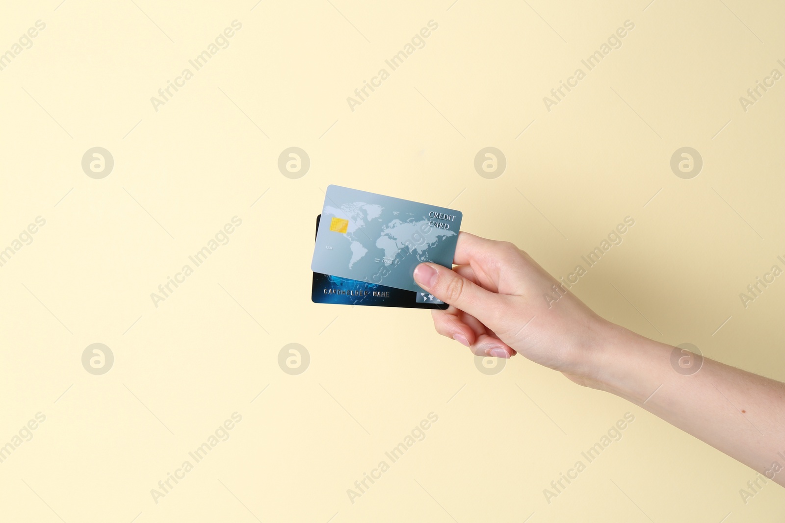 Photo of Woman holding credit cards on pale yellow background, closeup