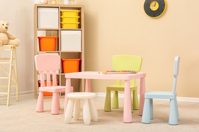 Cozy kids room interior with table, sofa and shelving unit