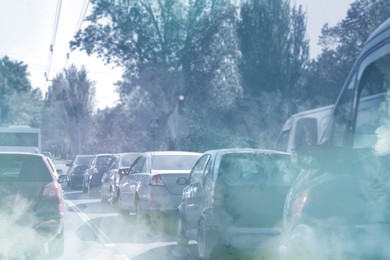 Image of Environmental pollution. Air contaminated with fumes in city. Cars surrounded by exhaust on road