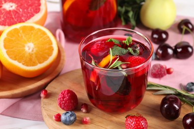 Photo of Glass of delicious sangria, fruits and berries on table, closeup