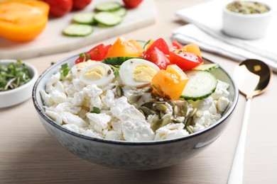 Photo of Fresh cottage cheese with vegetables, seeds and eggs in bowl on wooden table, closeup