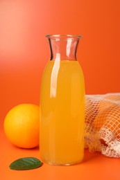 Net bag with fresh oranges and juice in bottle on color background, closeup