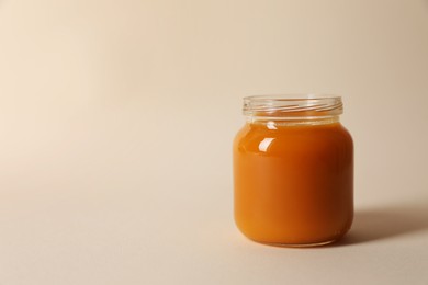 Photo of Jar with healthy baby food on beige background. Space for text