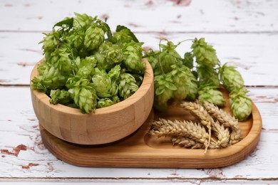 Photo of Fresh green hops and ears of wheat on white wooden table, closeup