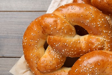 Photo of Delicious pretzels with sesame seeds on wooden table, closeup