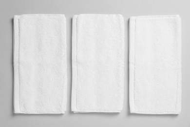 Photo of Soft folded white towels on light grey background, flat lay