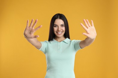 Photo of Woman showing number ten with her hands on yellow background