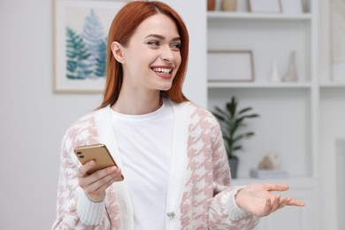 Photo of Happy woman sending message via smartphone at home