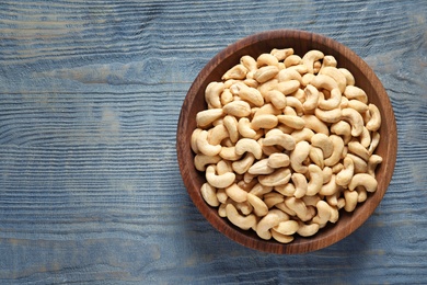 Tasty cashew nuts in bowl on wooden table, top view. Space for text
