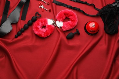 Photo of Sex toys and accessories on red fabric, flat lay. Space for text