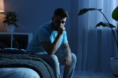 Photo of Frustrated man sitting on bed at night