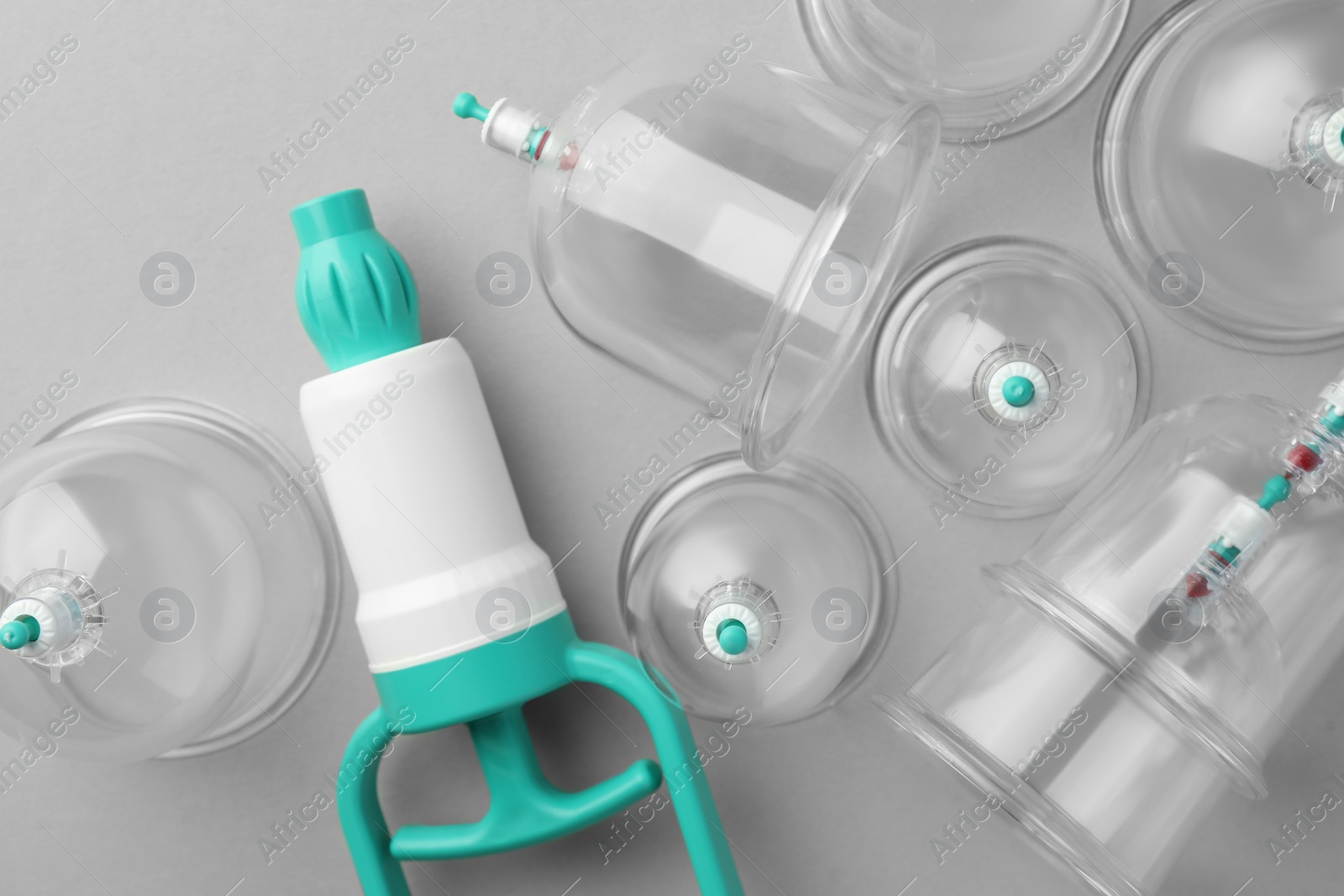 Photo of Plastic cups and hand pump on light grey background, flat lay. Cupping therapy
