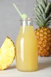 Photo of Delicious pineapple juice and fresh fruit on white wooden table