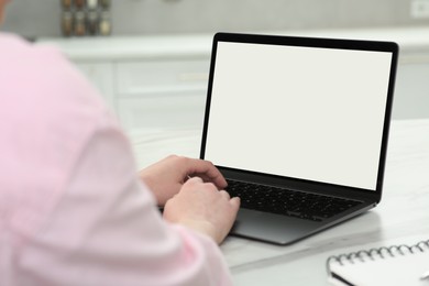 Woman using laptop at white table indoors, closeup