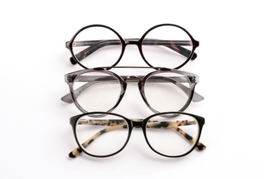 Photo of Different glasses with corrective lenses on white background. Vision problem