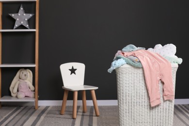 Photo of Laundry basket with baby clothes in child room