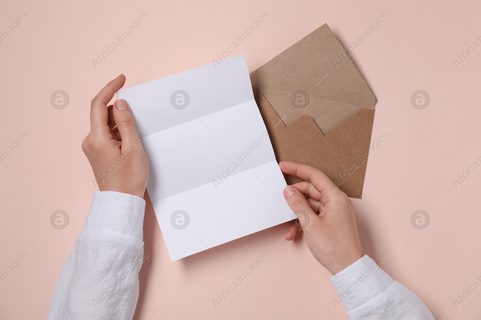 Photo of Woman with blank paper sheet at beige table, top view. Space for text