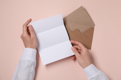 Photo of Woman with blank paper sheet at beige table, top view. Space for text