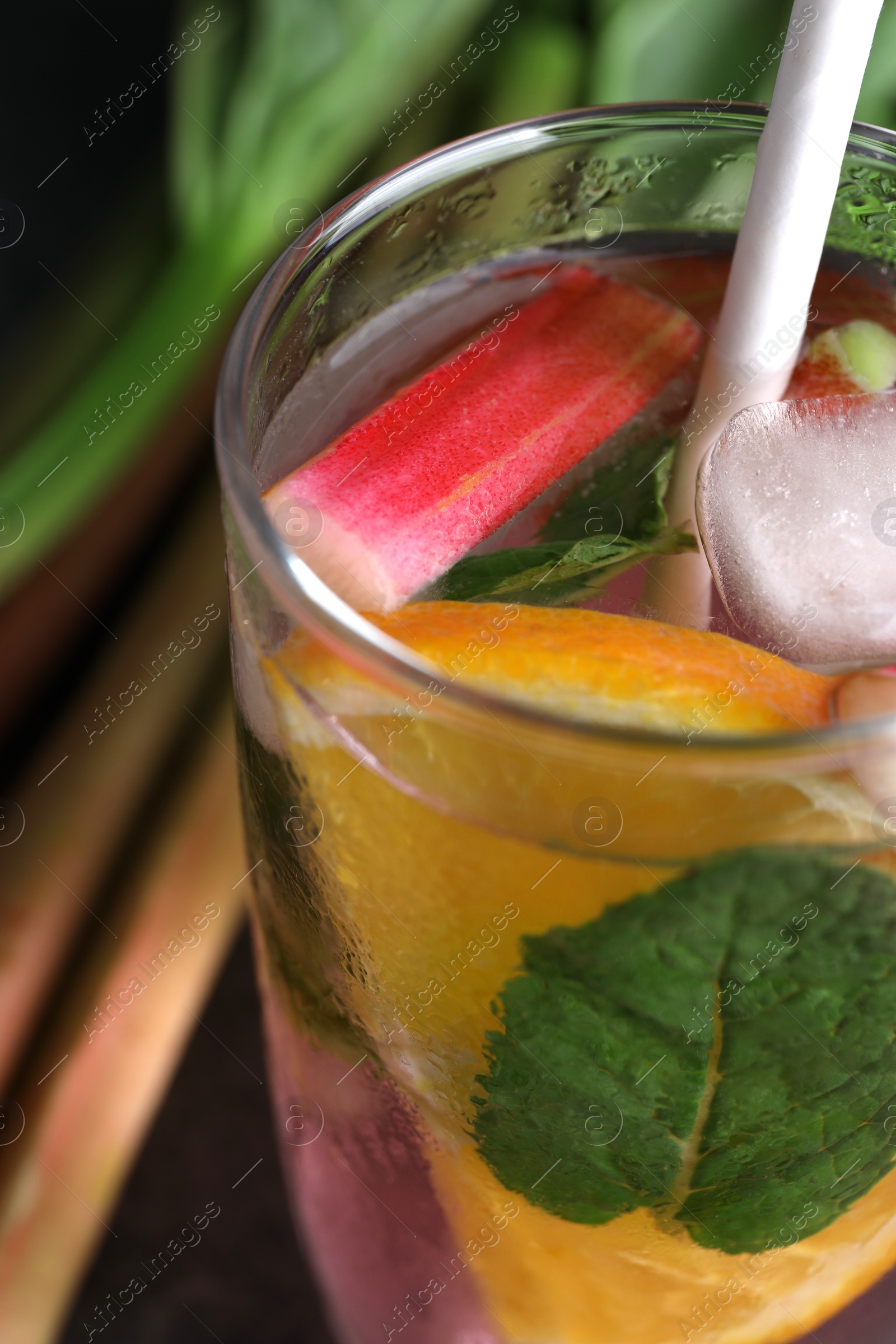 Photo of Glass of tasty rhubarb cocktail with lemon on table, closeup