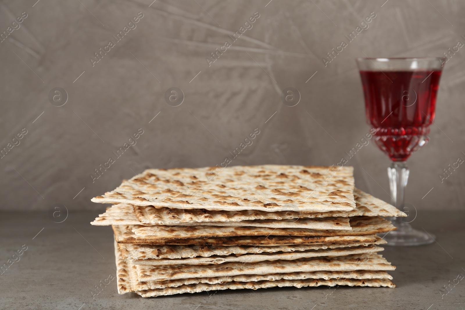 Photo of Passover matzos and glass of wine on grey table. Pesach celebration
