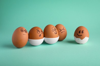 Photo of Eggs with drawn faces on turquoise background. Exhibitionist concept