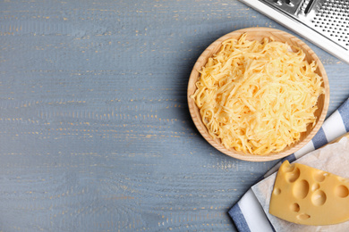 Photo of Tasty grated cheese on light grey wooden table, flat lay. Space for text