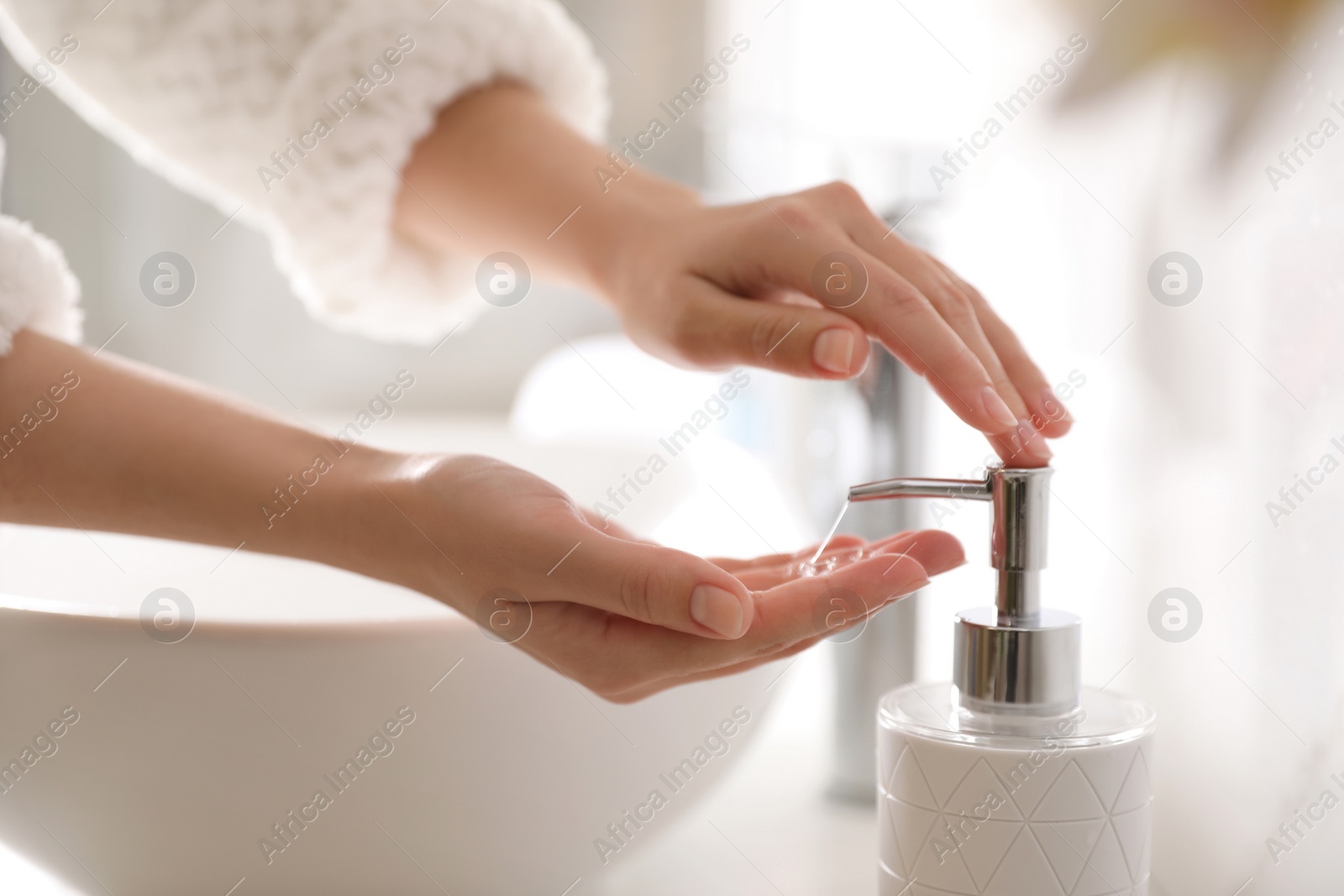 Photo of Woman using soap dispenser in bathroom, closeup