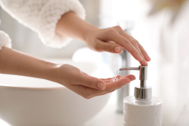 Woman using soap dispenser in bathroom, closeup