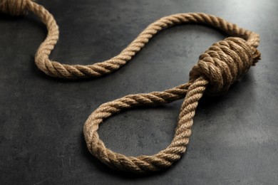 Photo of Rope noose with knot on grey table, closeup