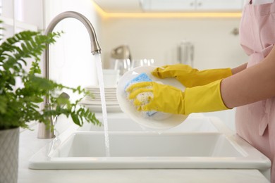 Photo of Woman washing plate in modern kitchen, closeup