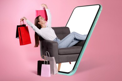 Online shopping. Happy woman with paper bags in armchair looking out from smartphone on pink background