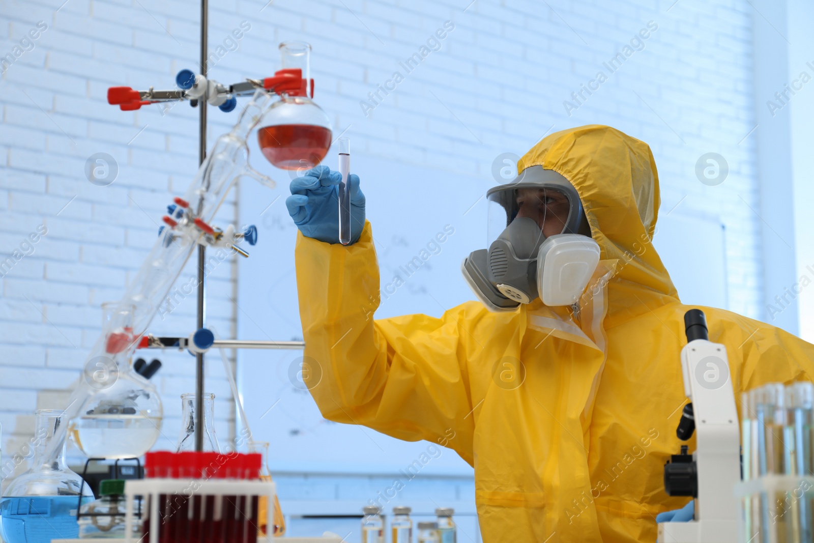 Photo of Scientist in chemical protective suit with test tube at laboratory. Virus research