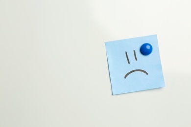 Photo of Sticker with sad face on white background, top view. Space for text