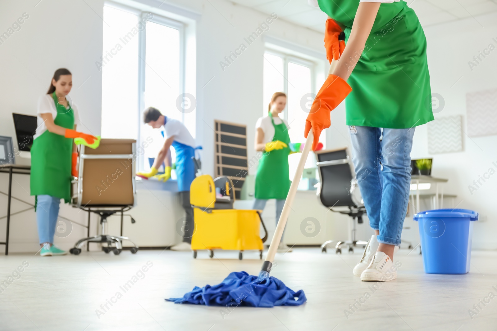 Photo of Team of professional janitors in uniform cleaning office