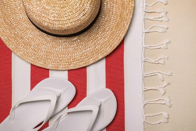 Photo of Beach towel, hat and flip flops on sand, flat lay
