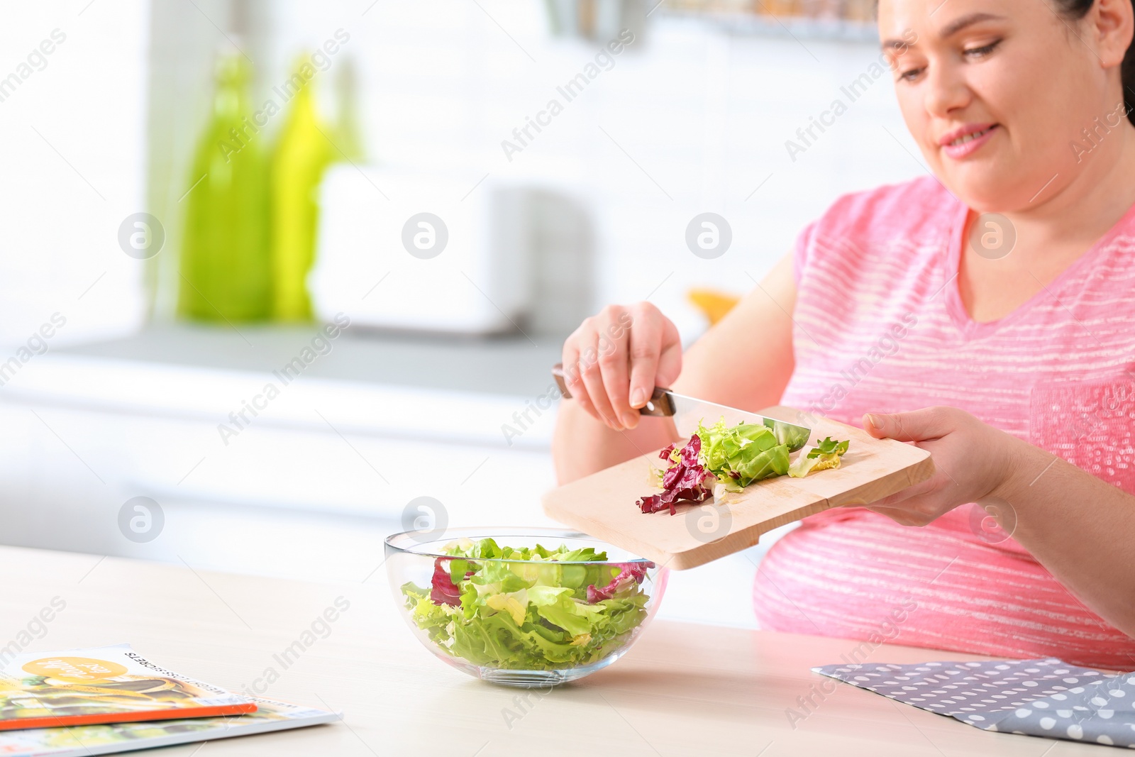 Photo of Overweight woman preparing salad in kitchen, space for text. Healthy diet