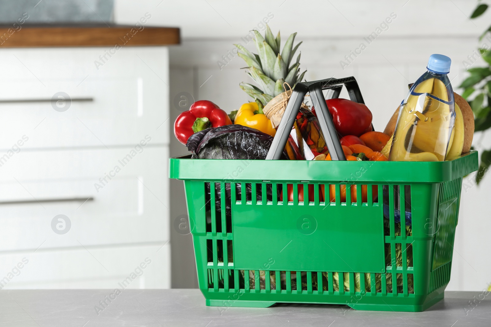 Photo of Shopping basket with grocery products on grey table indoors. Space for text