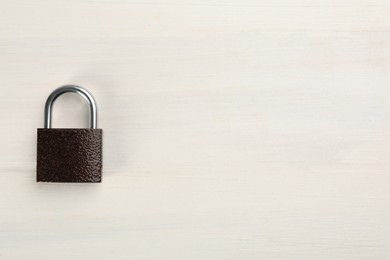 Photo of Modern padlock on white wooden table, top view. Space for text