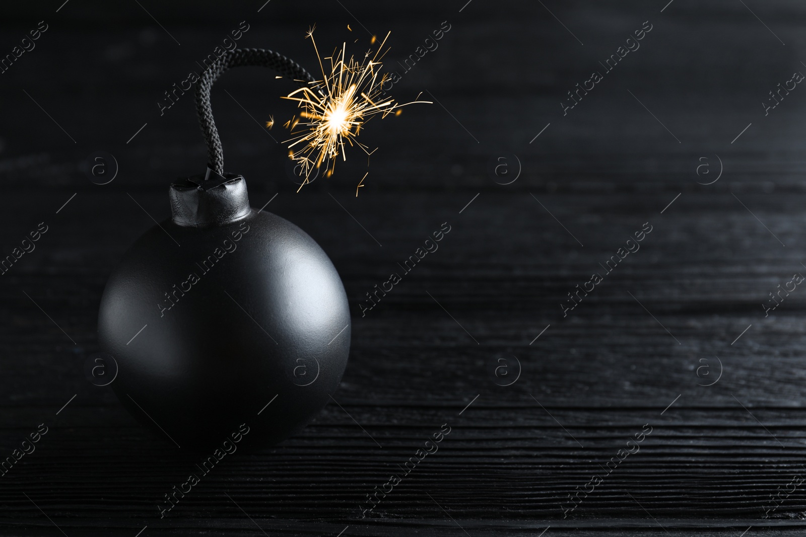 Photo of Old fashioned fuse bomb on black wooden table. Space for text